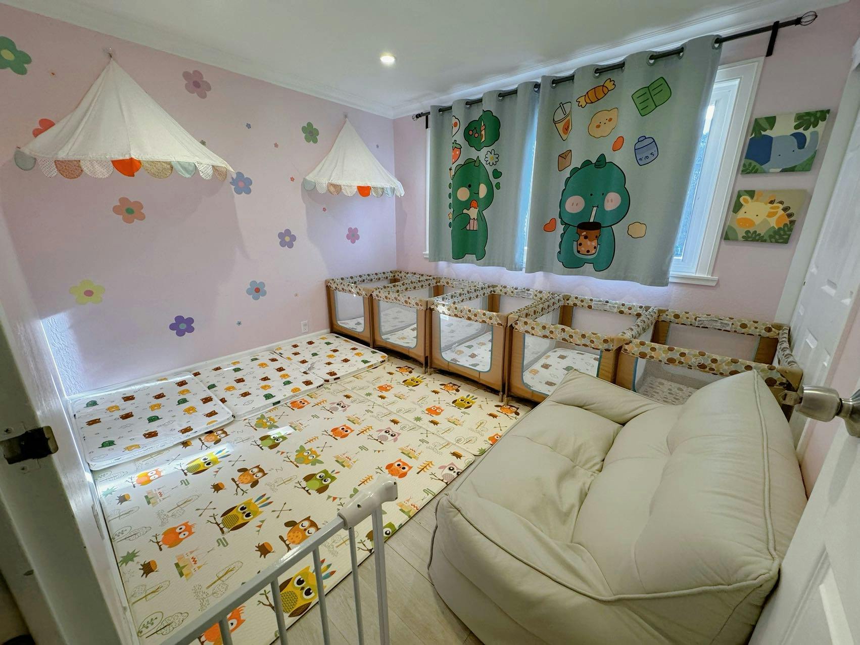 Playroom with soft floor mats, multiple cribs, and a beanbag chair