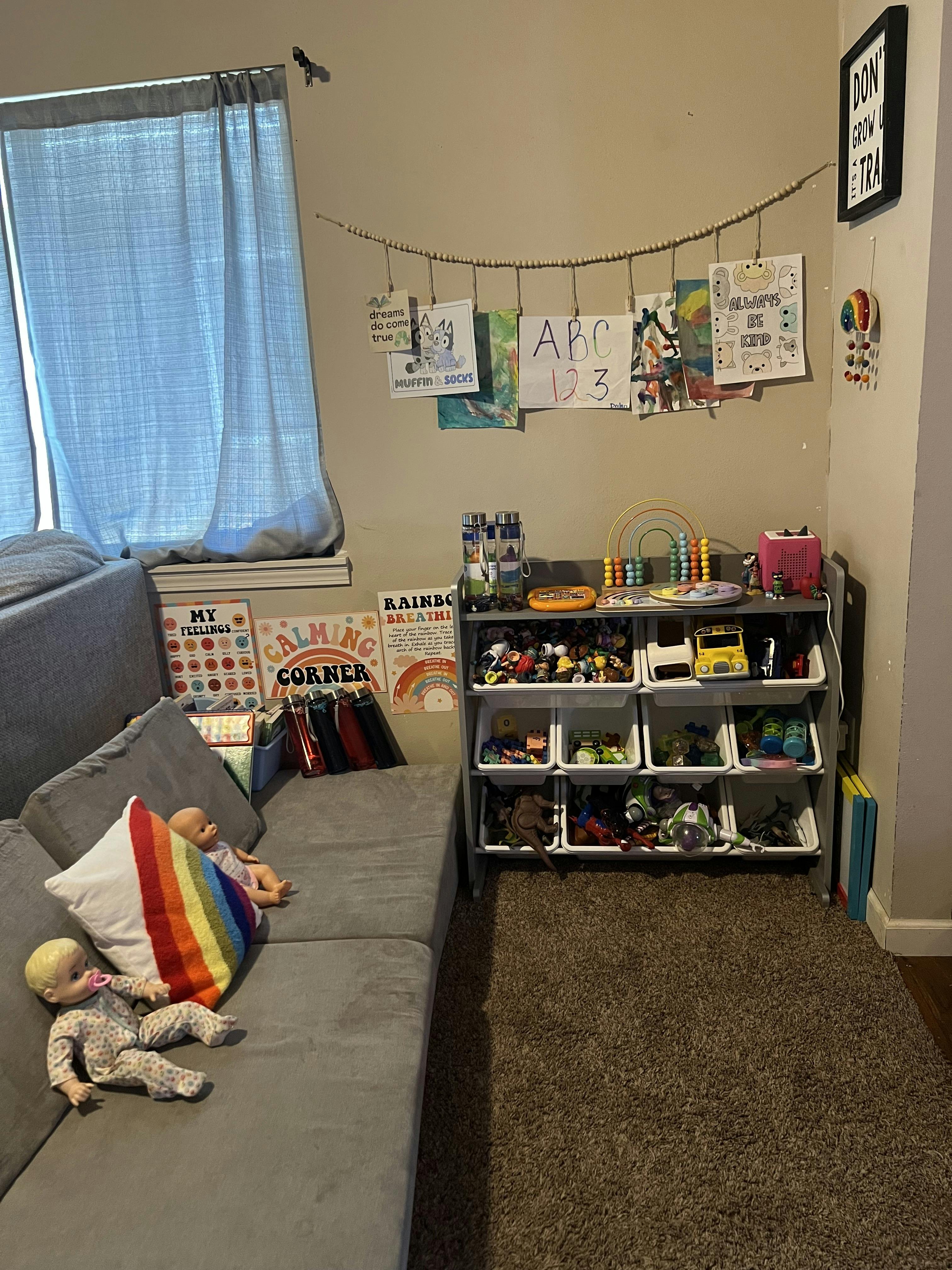 Children's room with a gray sofa, toy storage, and wall art