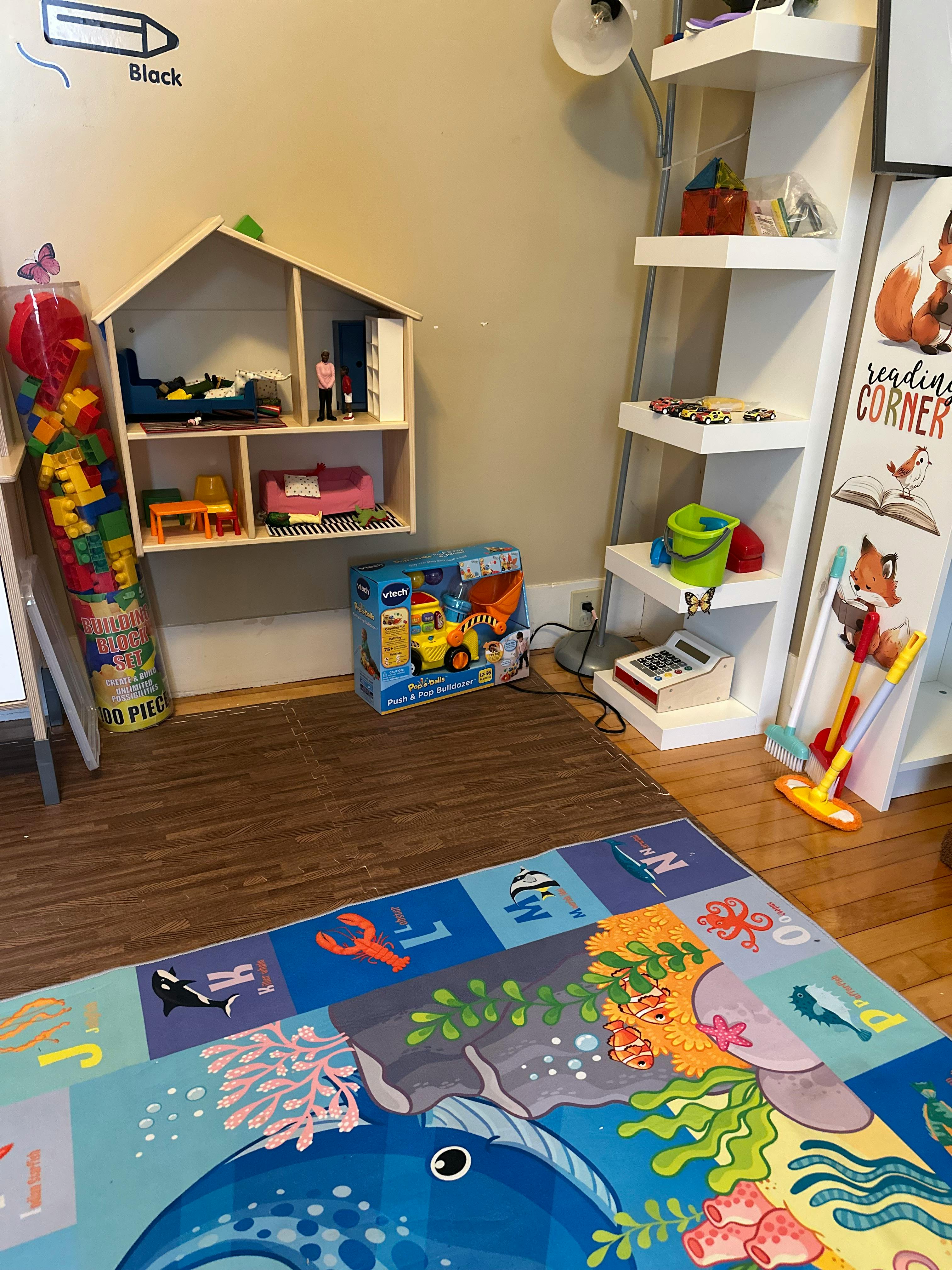 Playroom with dollhouse, toy shelf, and colorful playmat