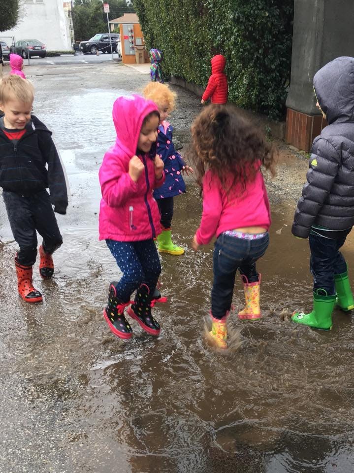 Children in rain boots playing in puddles