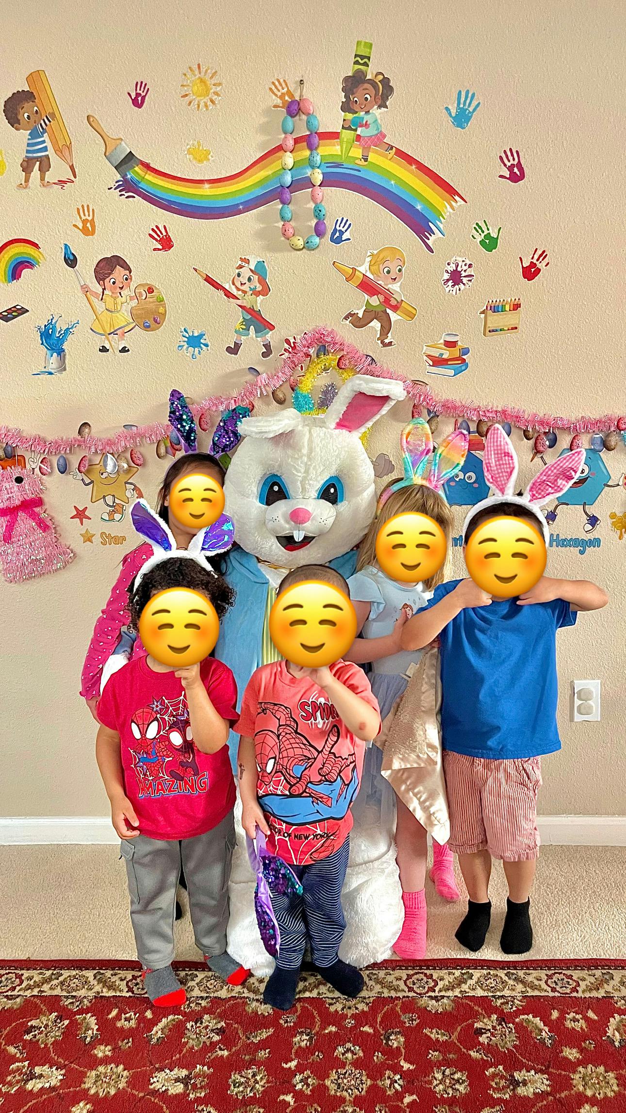 Children wearing bunny ears posing with a person in a bunny costume
