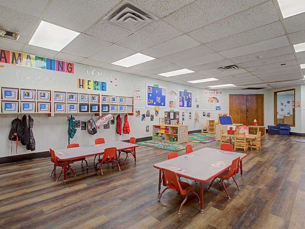 Classroom with small tables, chairs, and colorful decorations on the wall