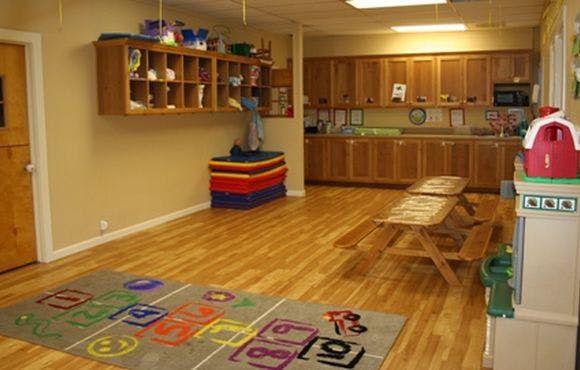 Playroom with wooden floor, hopscotch rug, and small picnic table