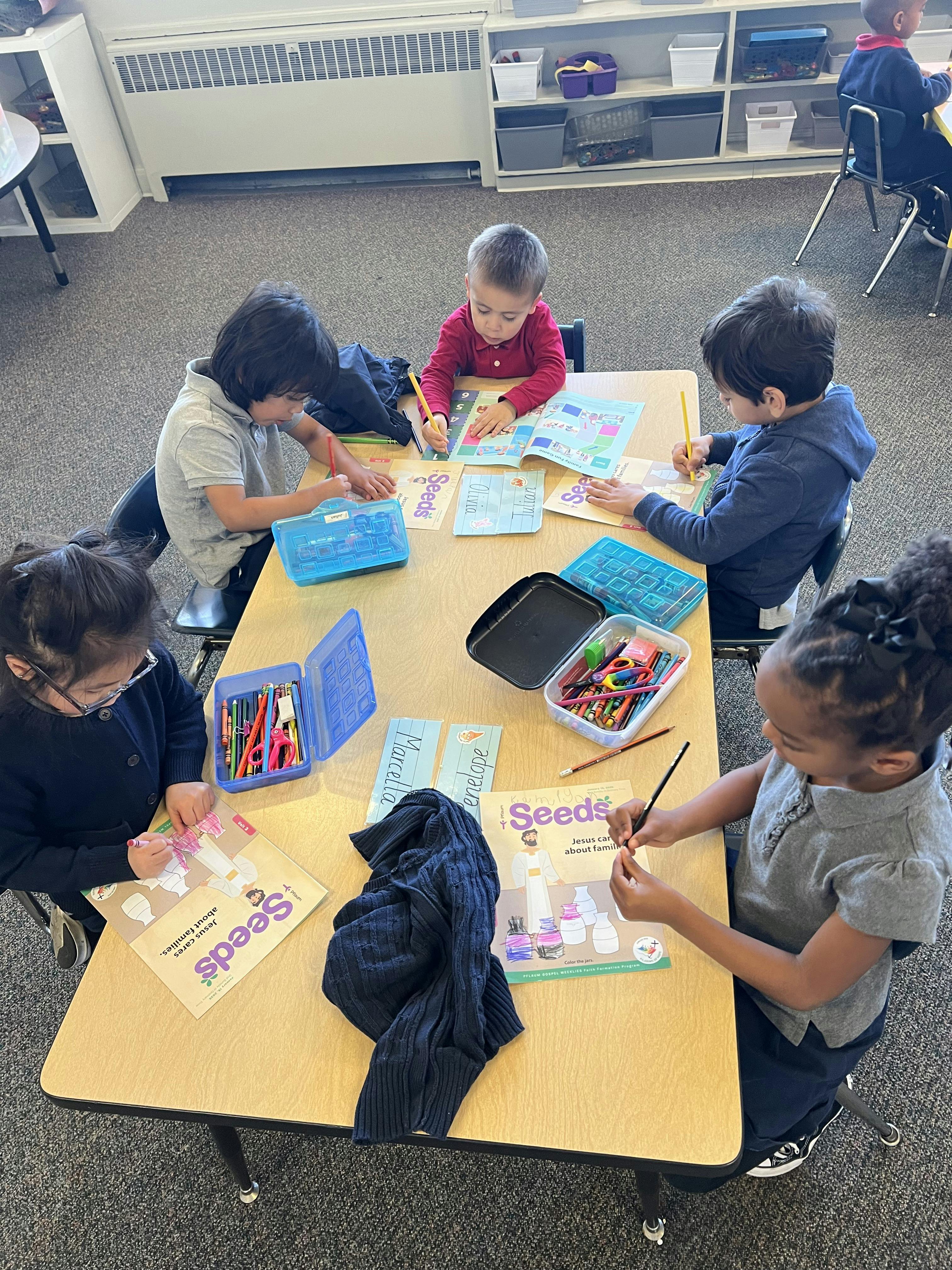 Children coloring and drawing at a table in a classroom