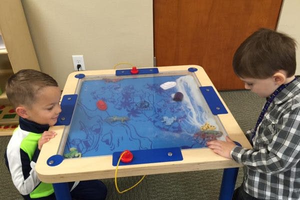 Two children playing with a water table