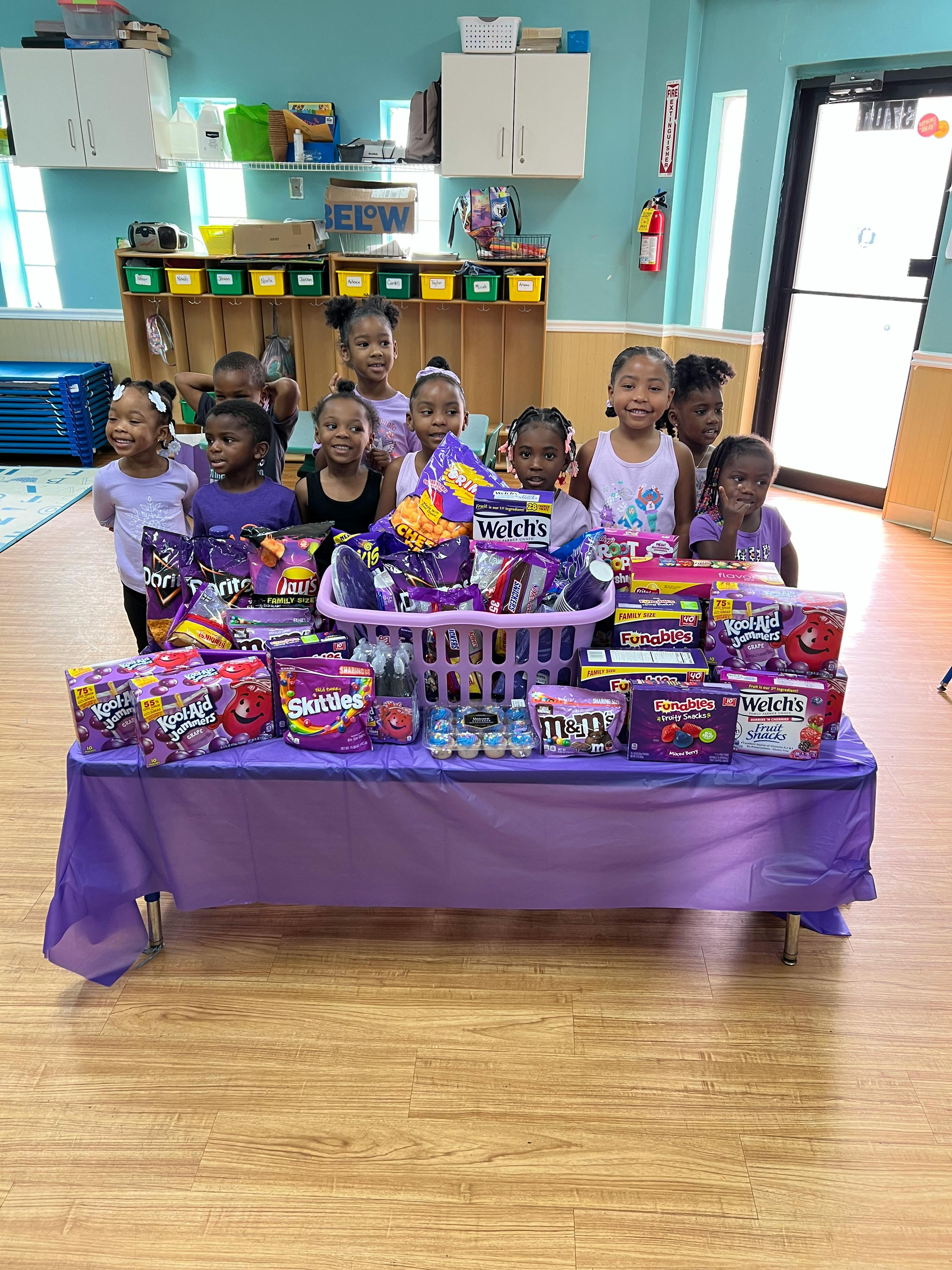 Group of children standing behind a table with snacks