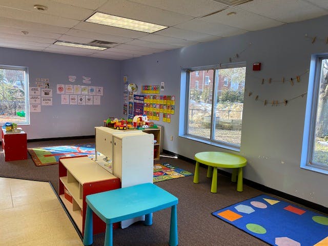 Playroom with colorful rugs, small tables, and toys