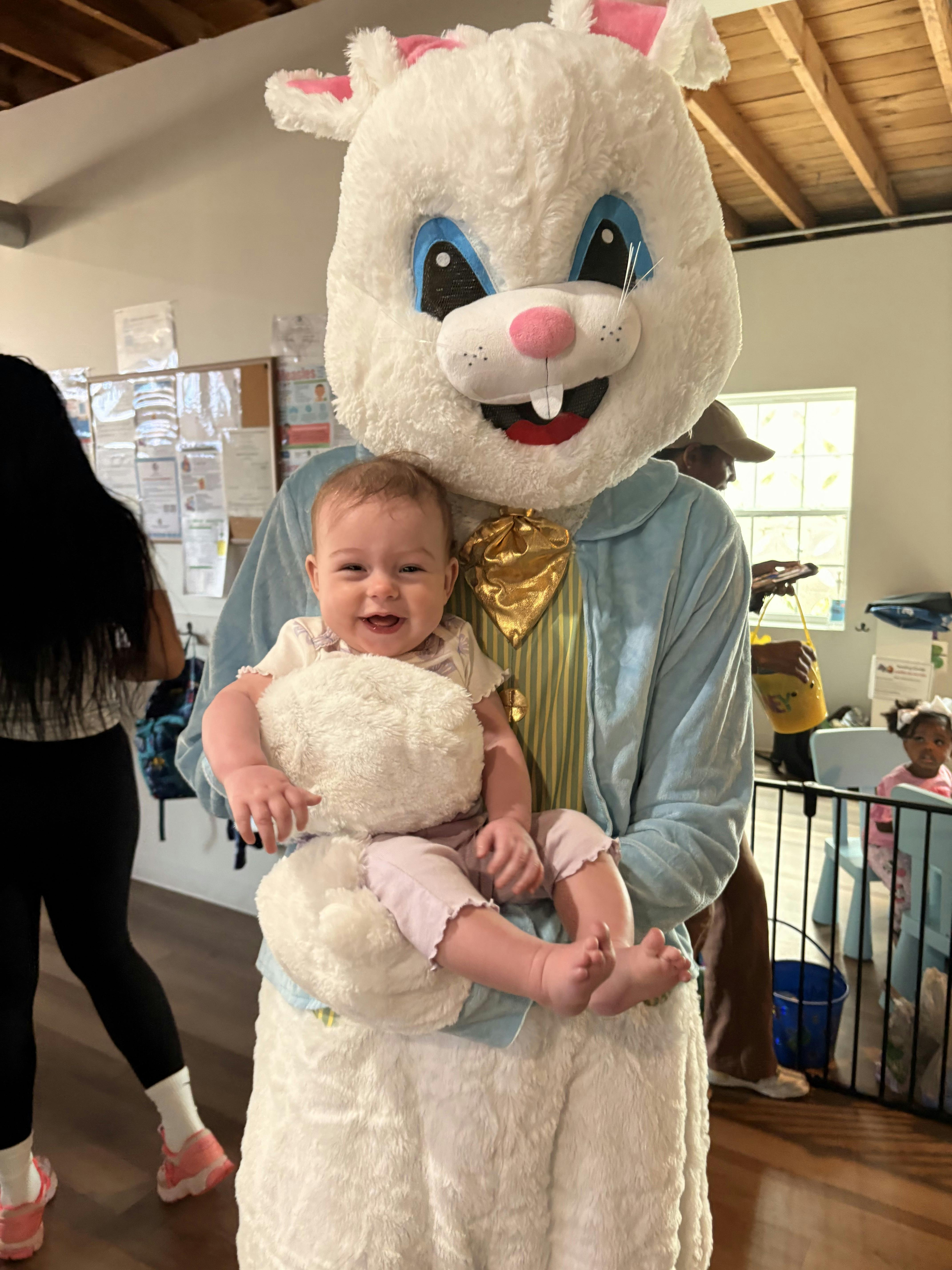A person in a large bunny costume holding an infant