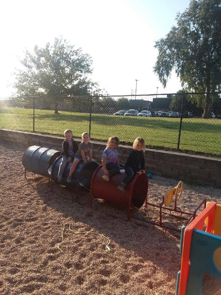 Four children sitting on a playground tunnel