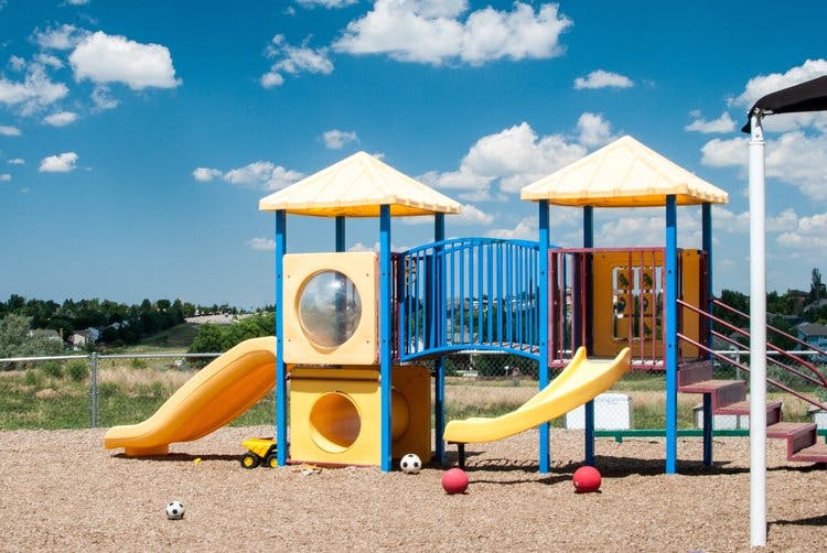 Playground with yellow slides and blue railings under a blue sky