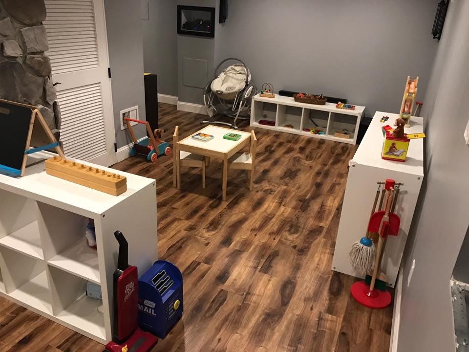 Playroom with small table and chairs, shelves with toys, and cleaning supplies