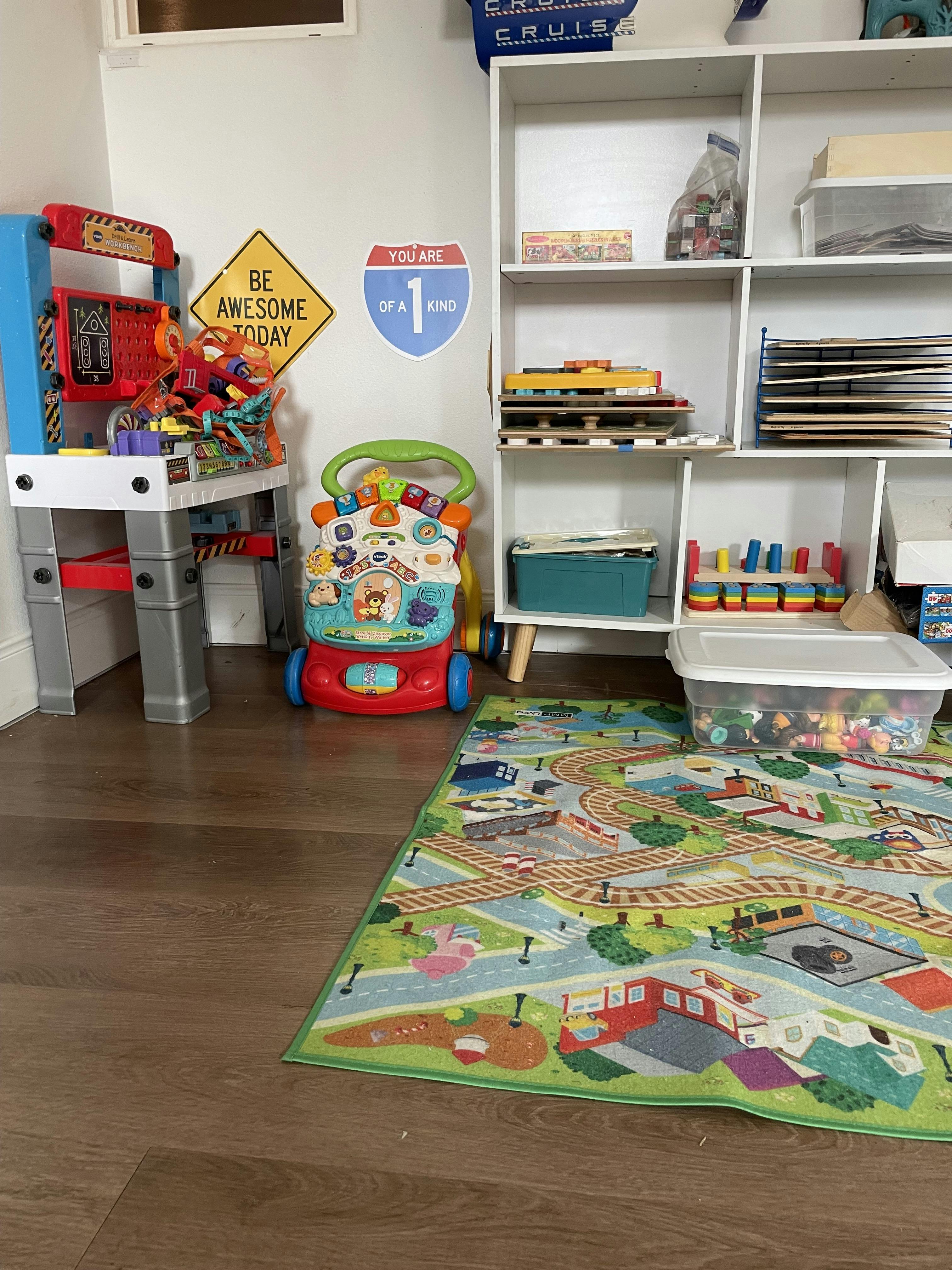 Children's play area with a workbench, activity walker, and a road map rug
