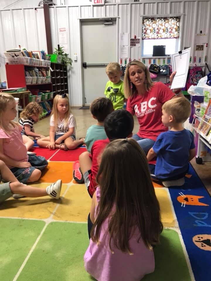 Adult and children sitting on floor in a classroom