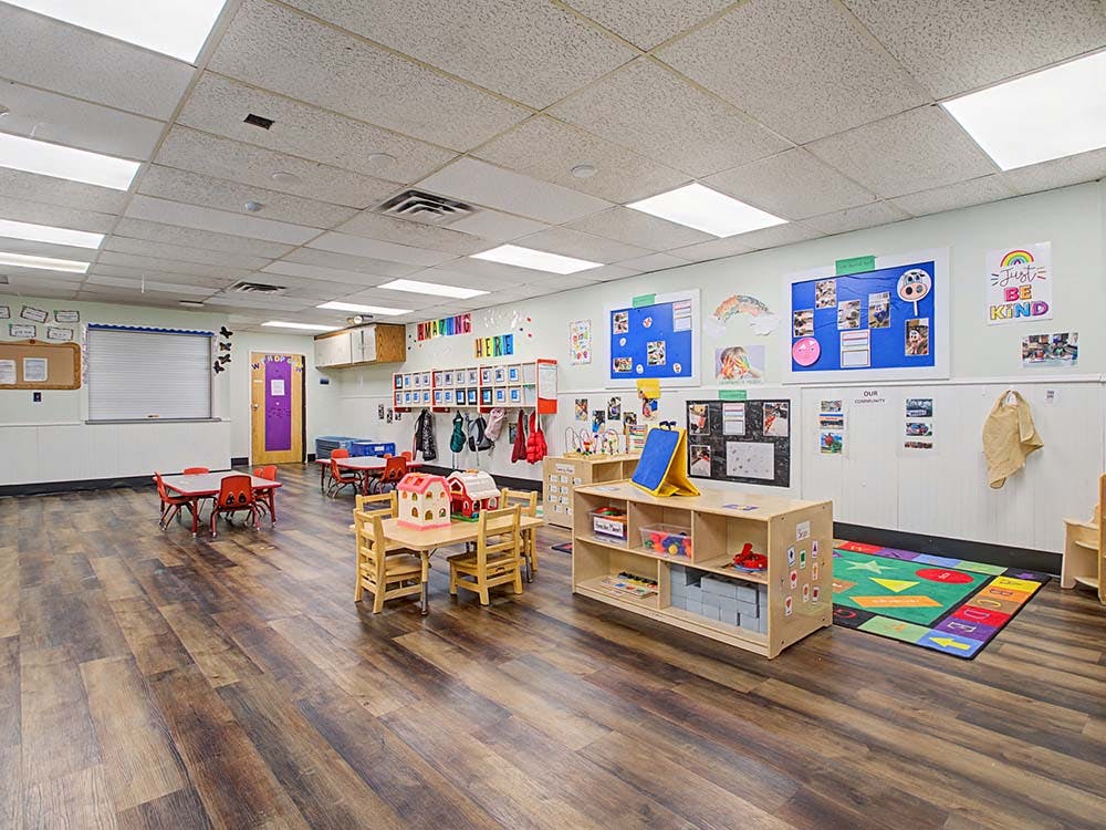 A classroom with small tables and chairs, shelves, and colorful wall decorations