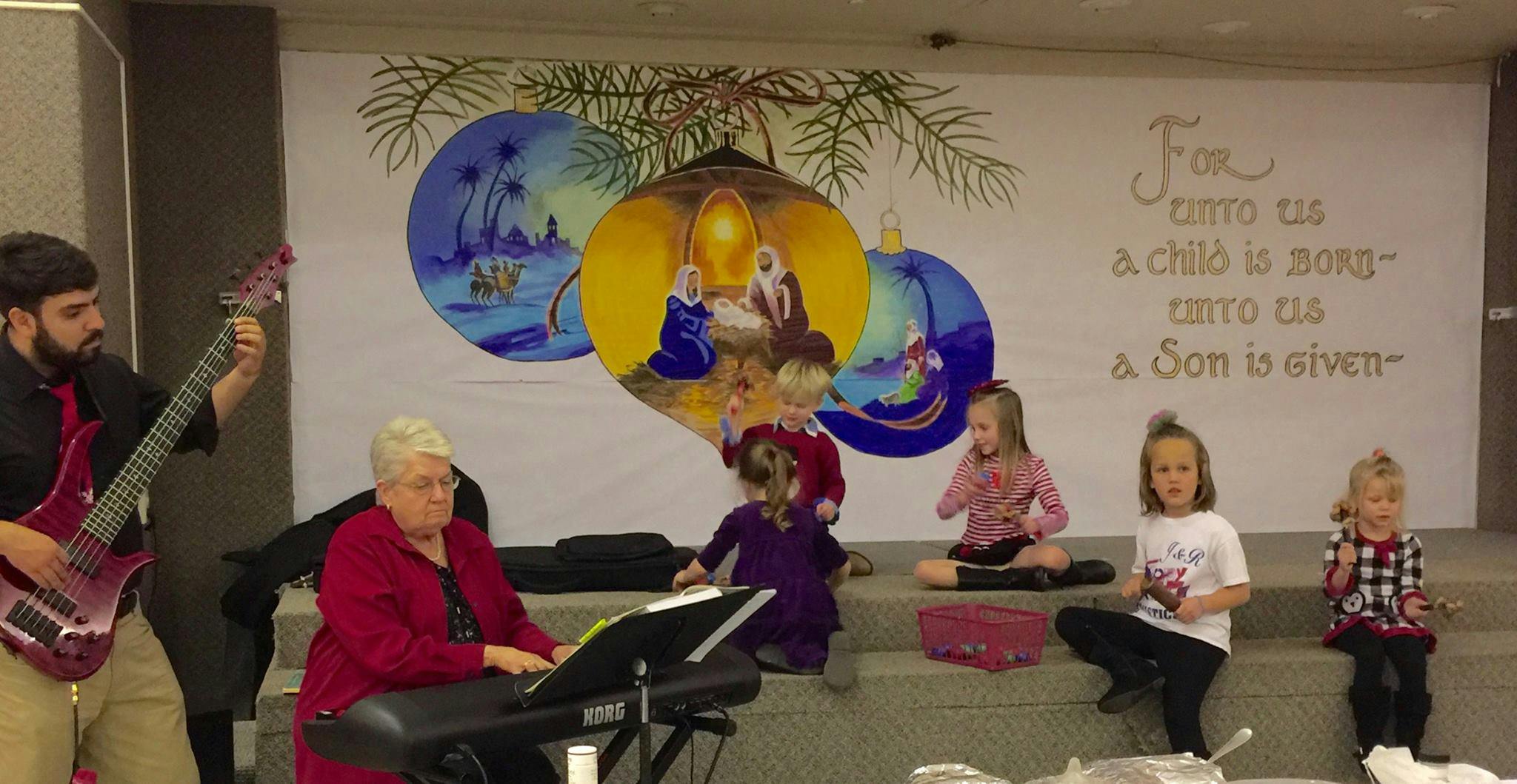 People playing instruments and children sitting in front of a mural