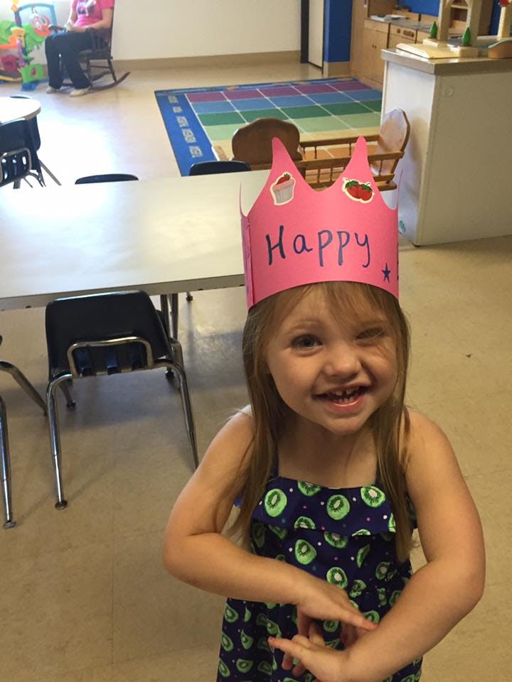 Child wearing a pink crown with "Happy" written on it