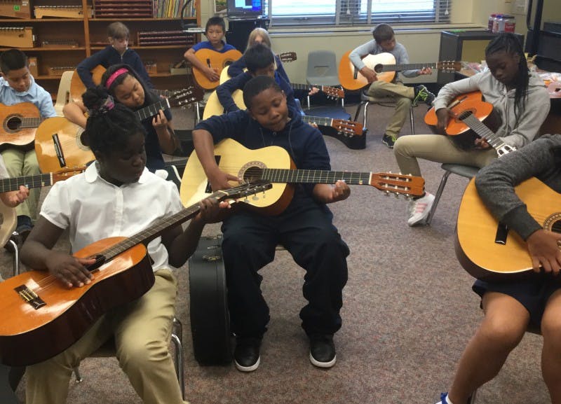 Group of children playing guitars in a classroom