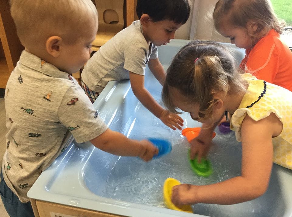 Children playing with water and toys in a sensory bin