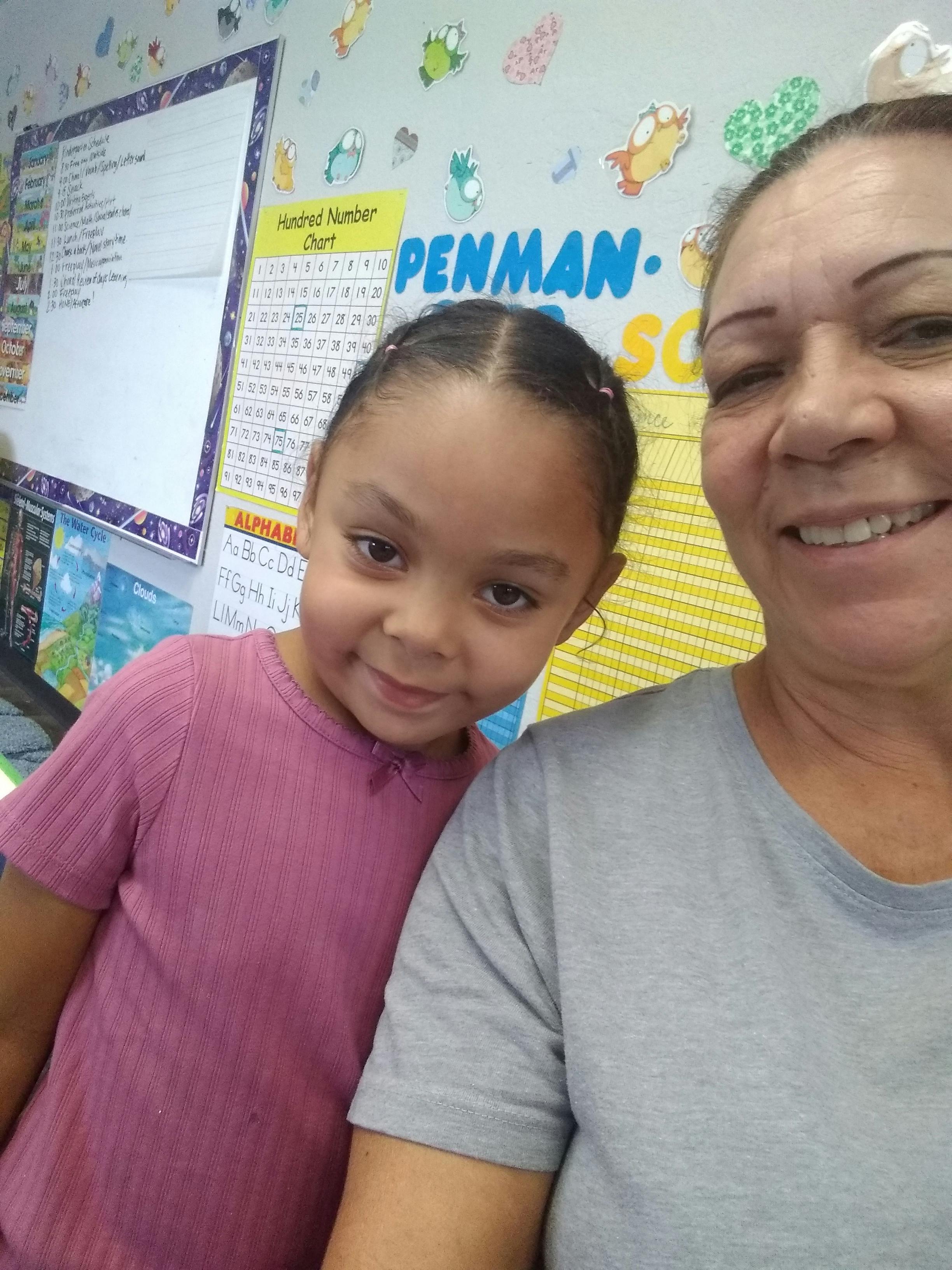 Adult and child in a classroom with educational posters in the background