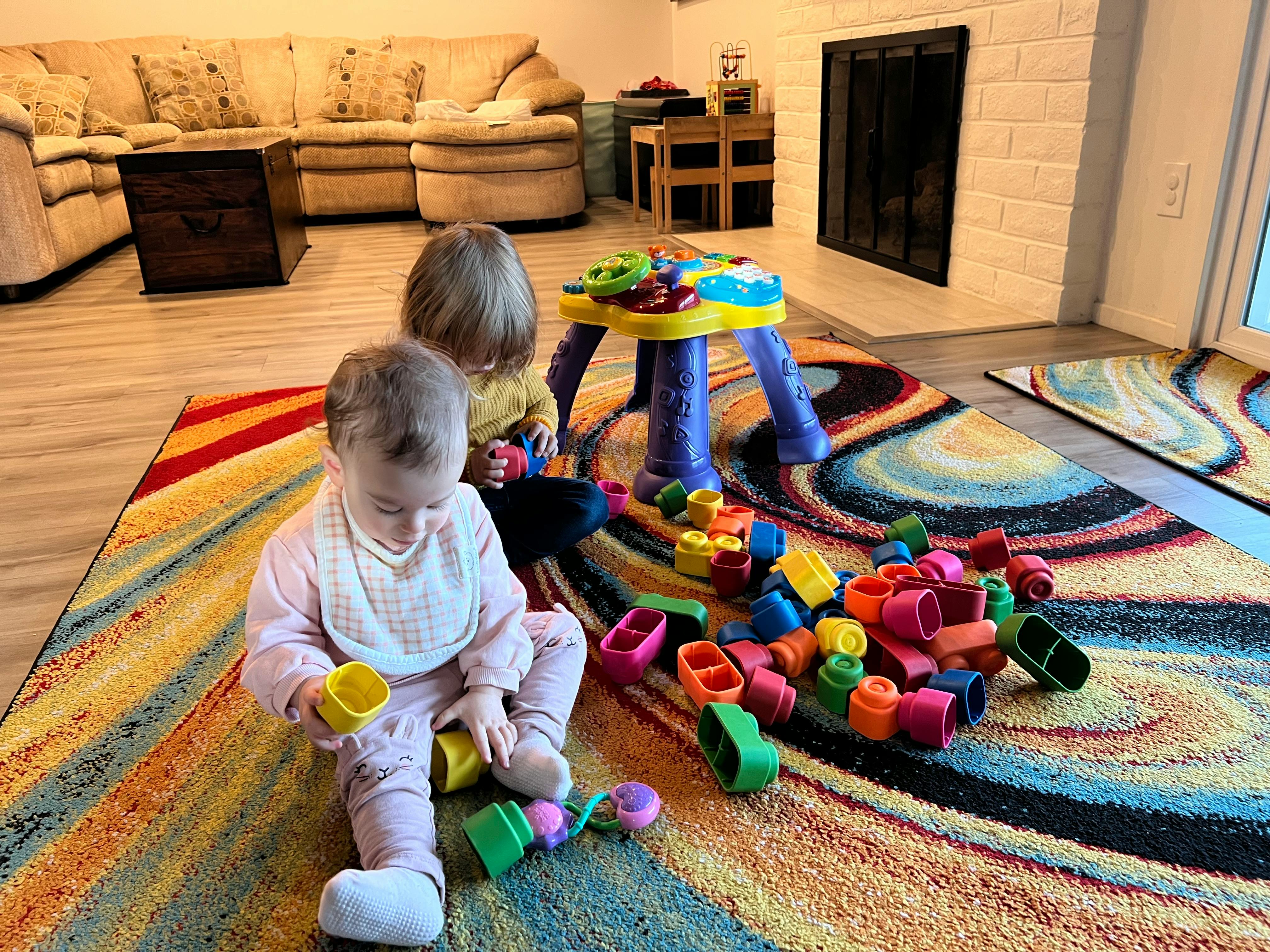Two children playing with colorful blocks on a rug