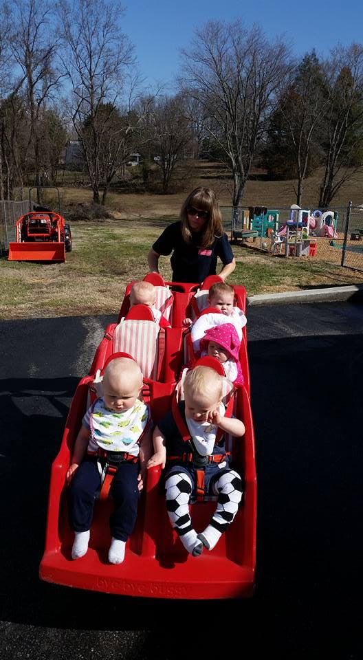Person pushing multiple children in a red stroller