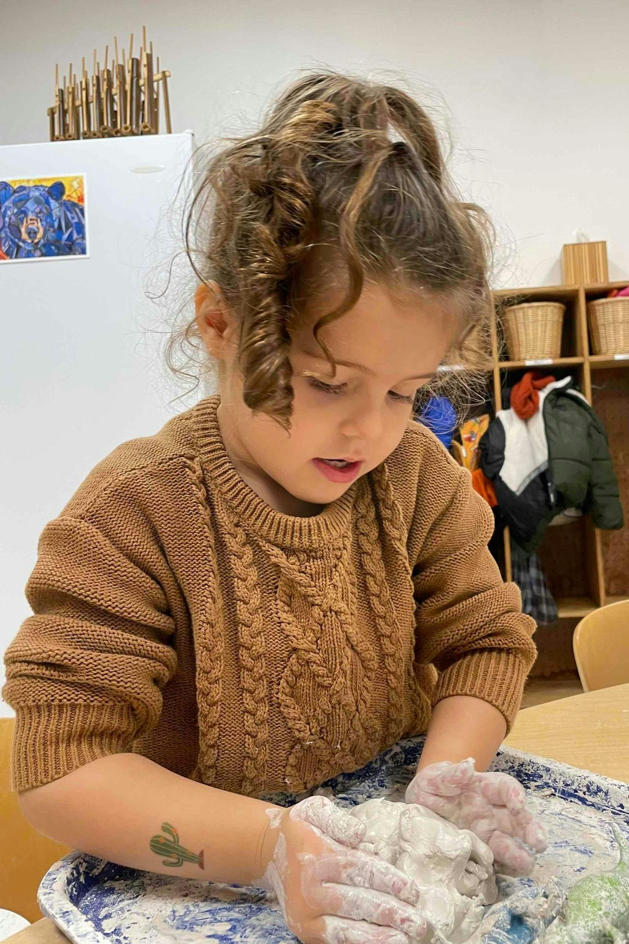 Child kneading dough in a tray
