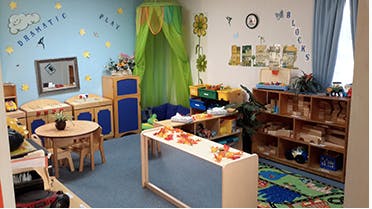 Playroom with small tables, chairs, and shelves