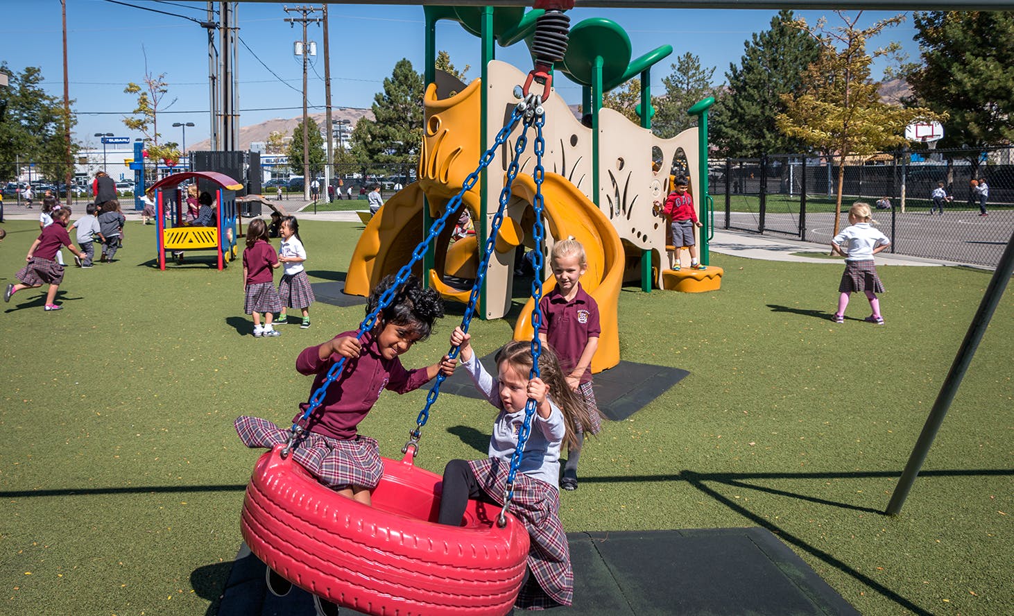 Children playing on a tire swing and playground equipment