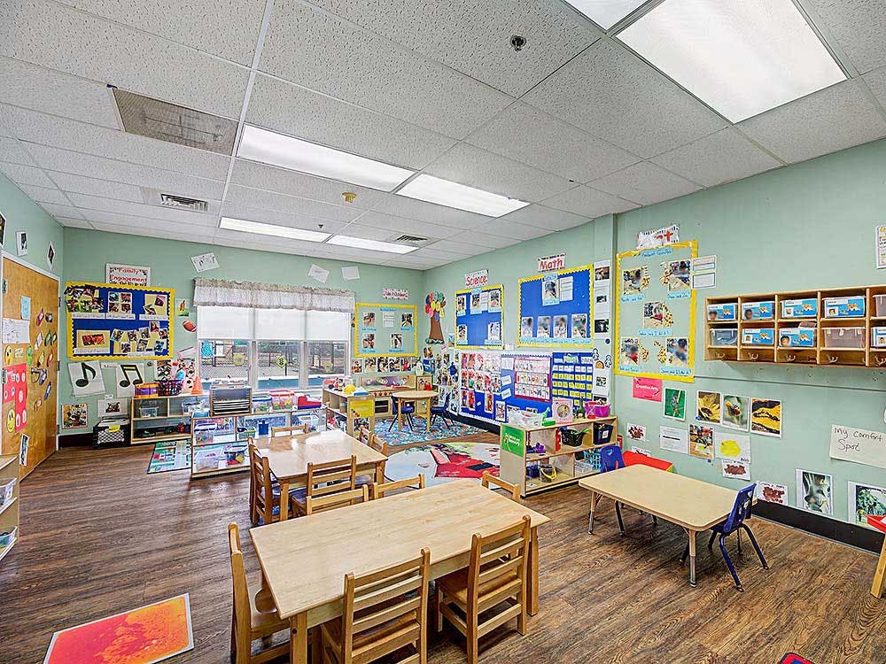A classroom with small tables and chairs, decorated walls with educational posters