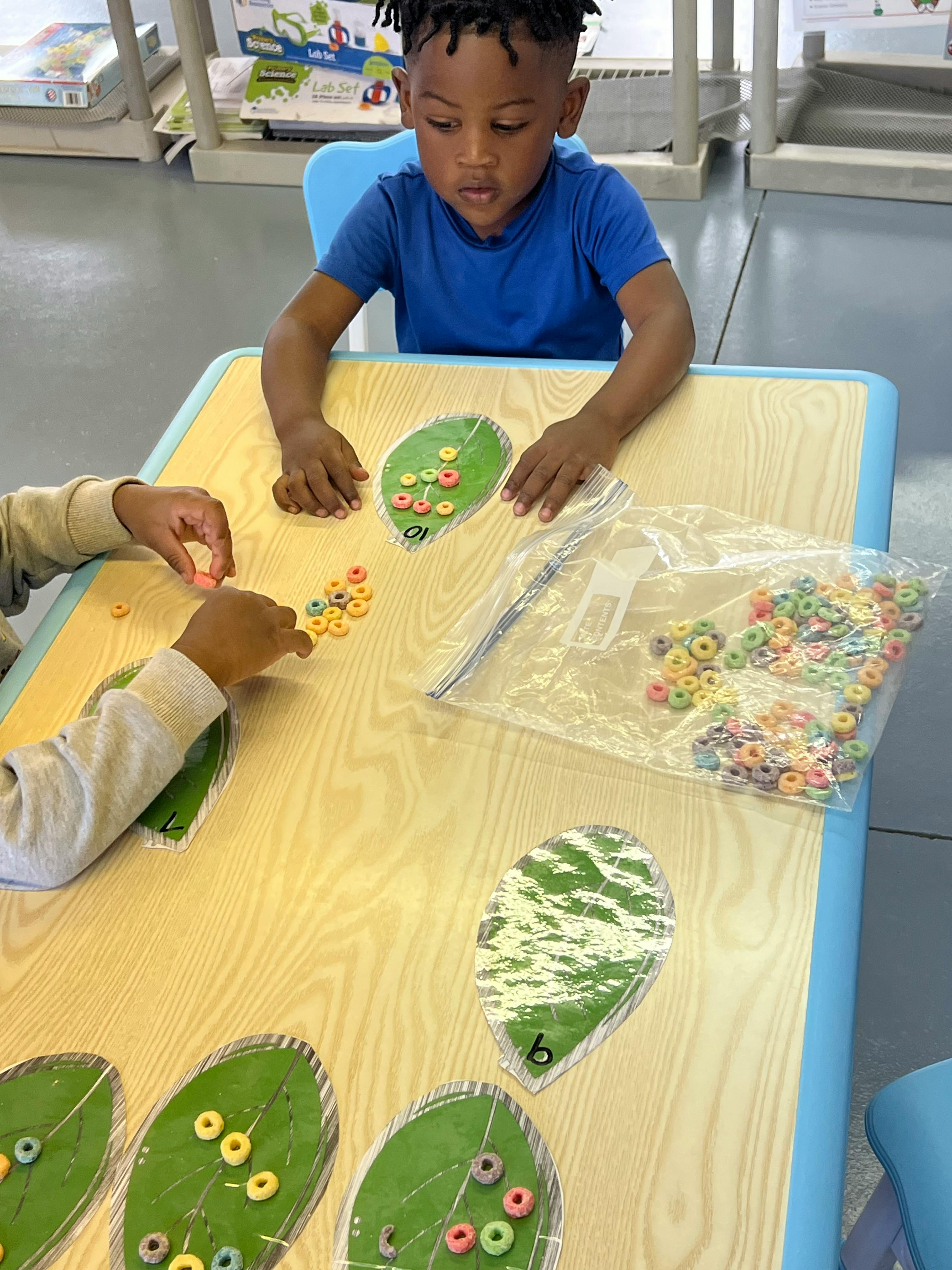 Two children playing a game with cereal pieces and leaf-shaped cards