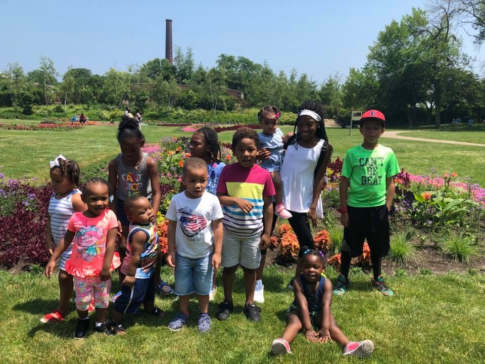 Group of children standing in a grassy area with flowers