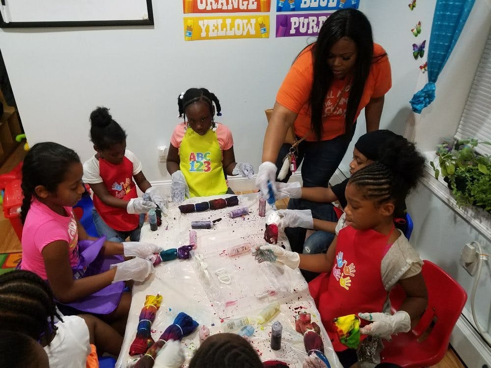 Adult and children tie-dyeing fabric at a table