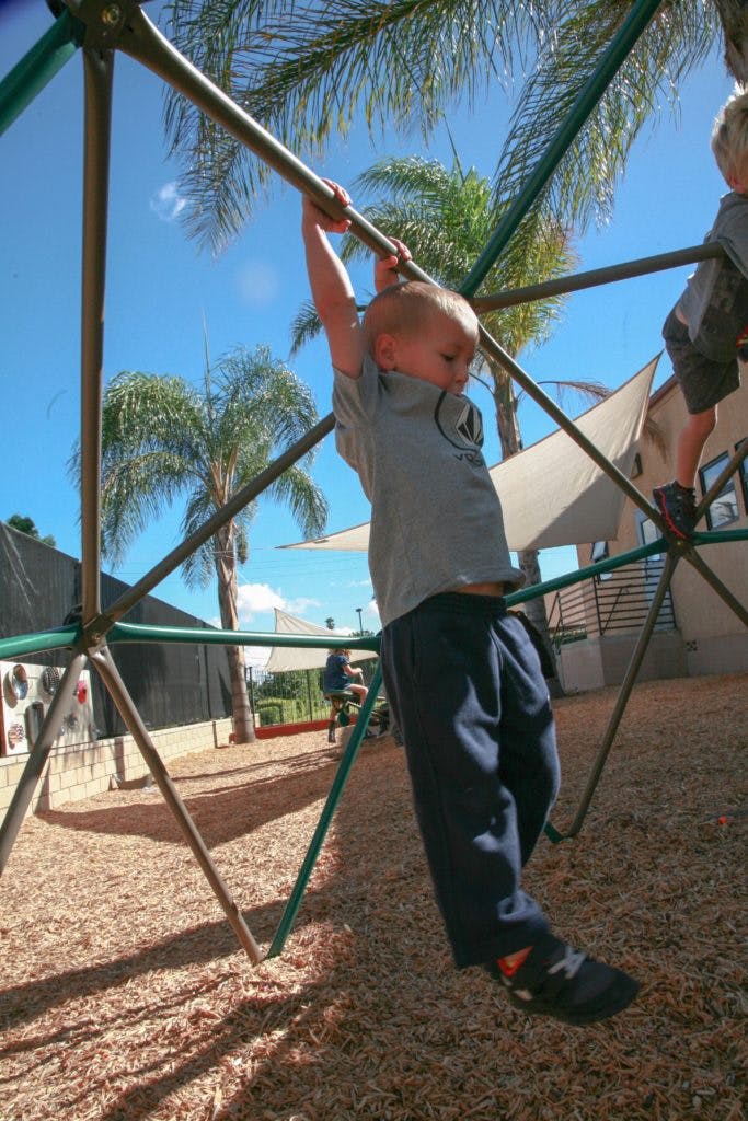 Child hanging from monkey bars on a playground