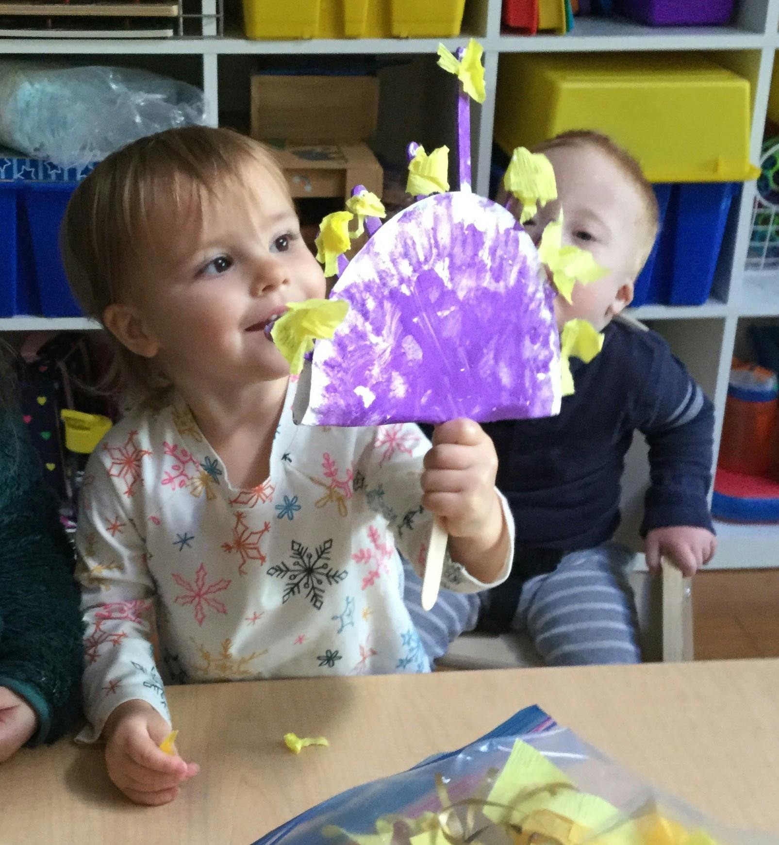 Child holding up a purple craft with yellow accents