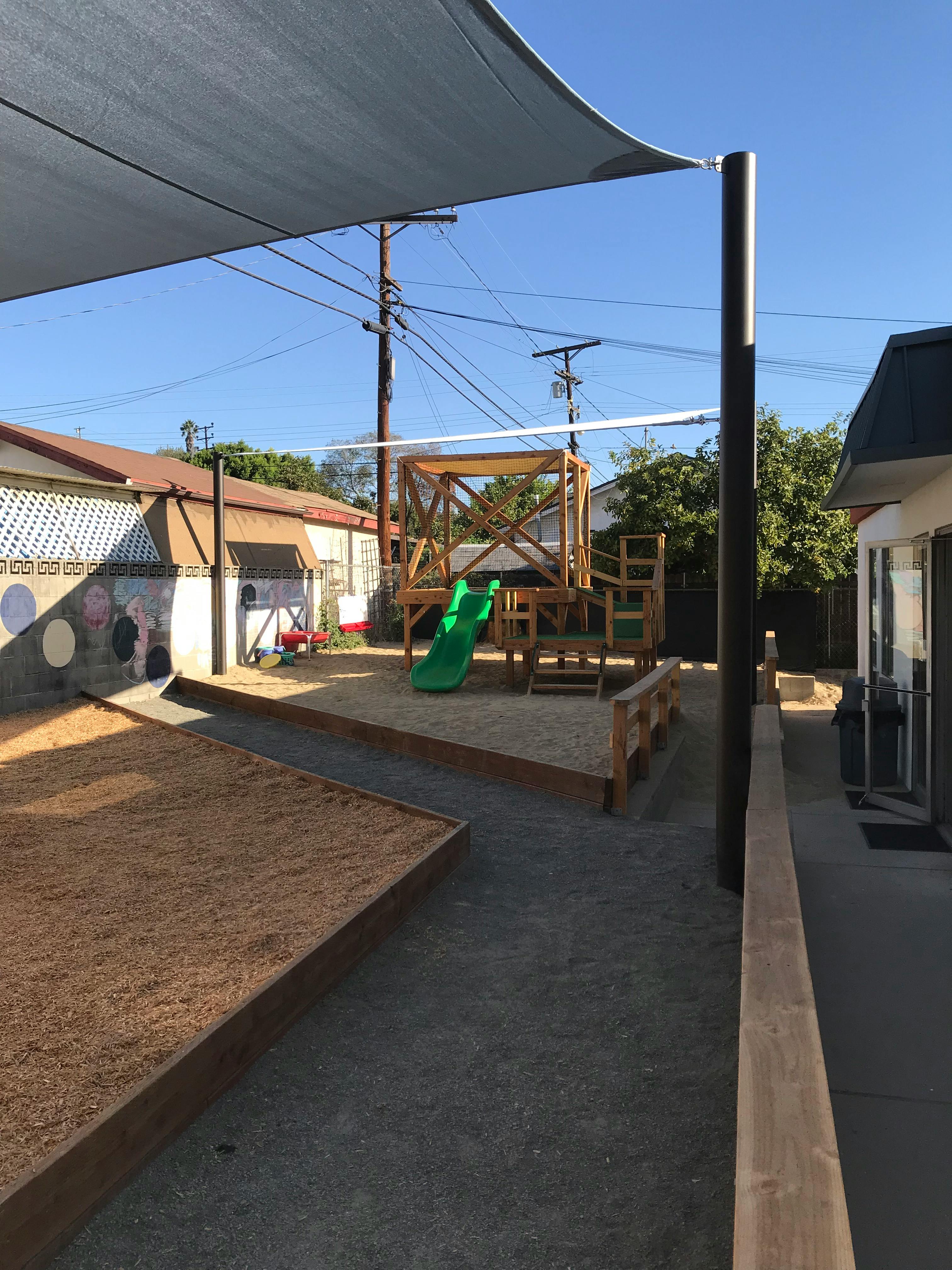 Outdoor play area with sandboxes and a wooden play structure with a green slide