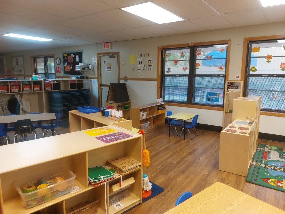 Empty classroom with small tables, chairs, and play areas