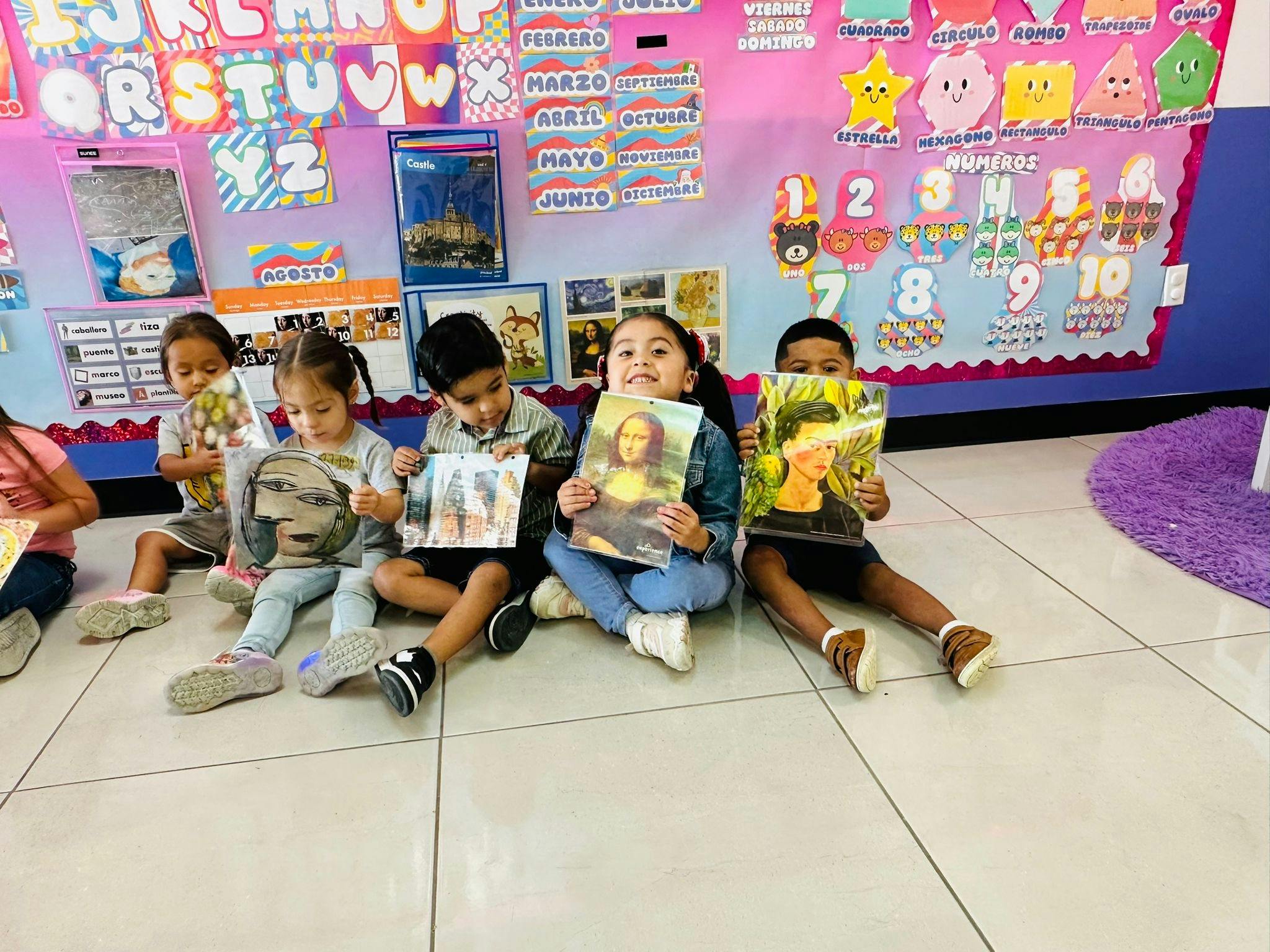 Children sitting on the floor holding books in front of them books with art on the covers