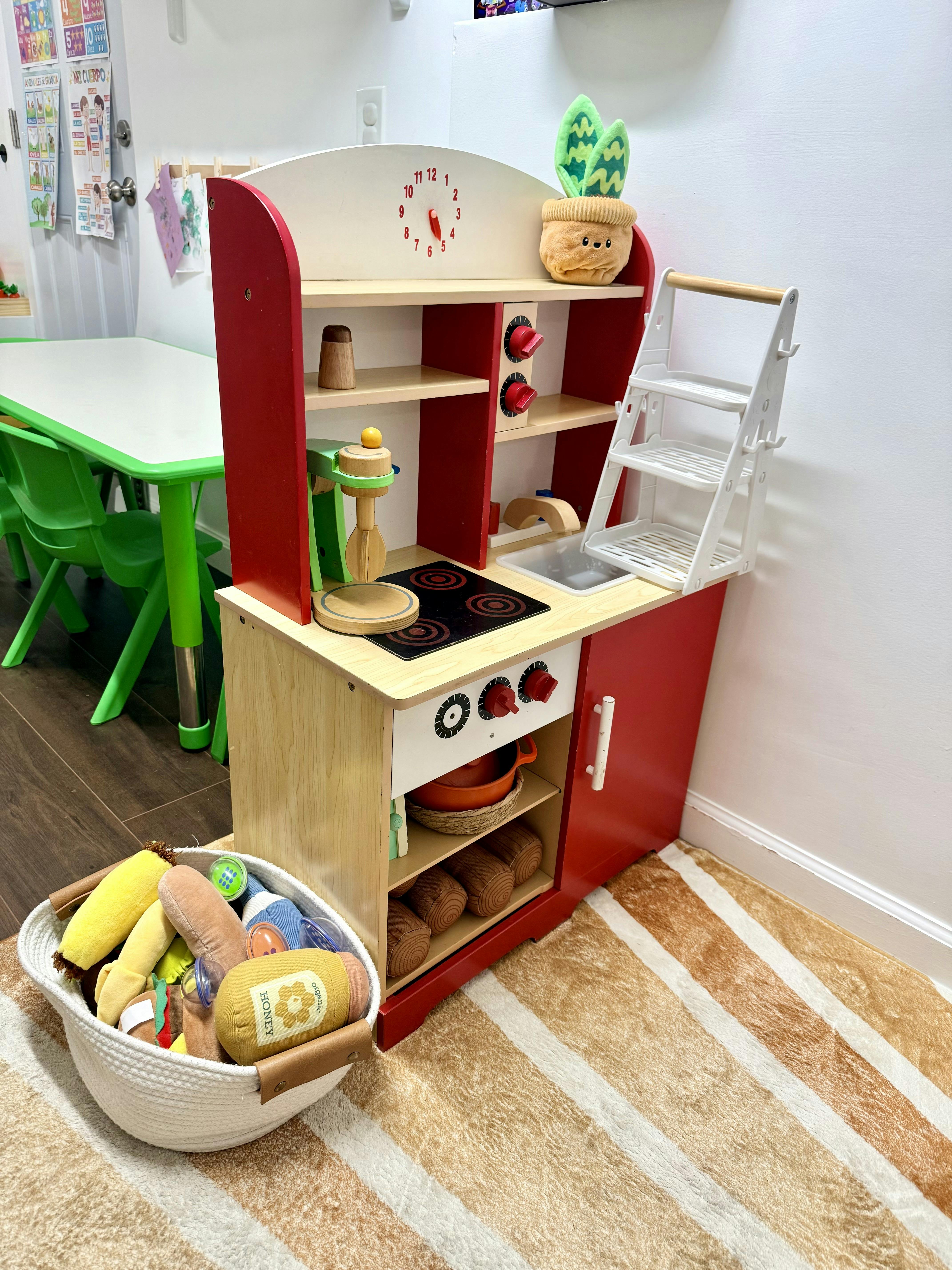 Toy wooden play kitchen with a basket of plush toy food items