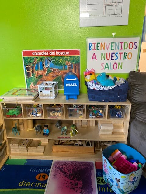 Classroom with a wooden shelf of toys and a "Bienvenidos a nuestro salon" sign