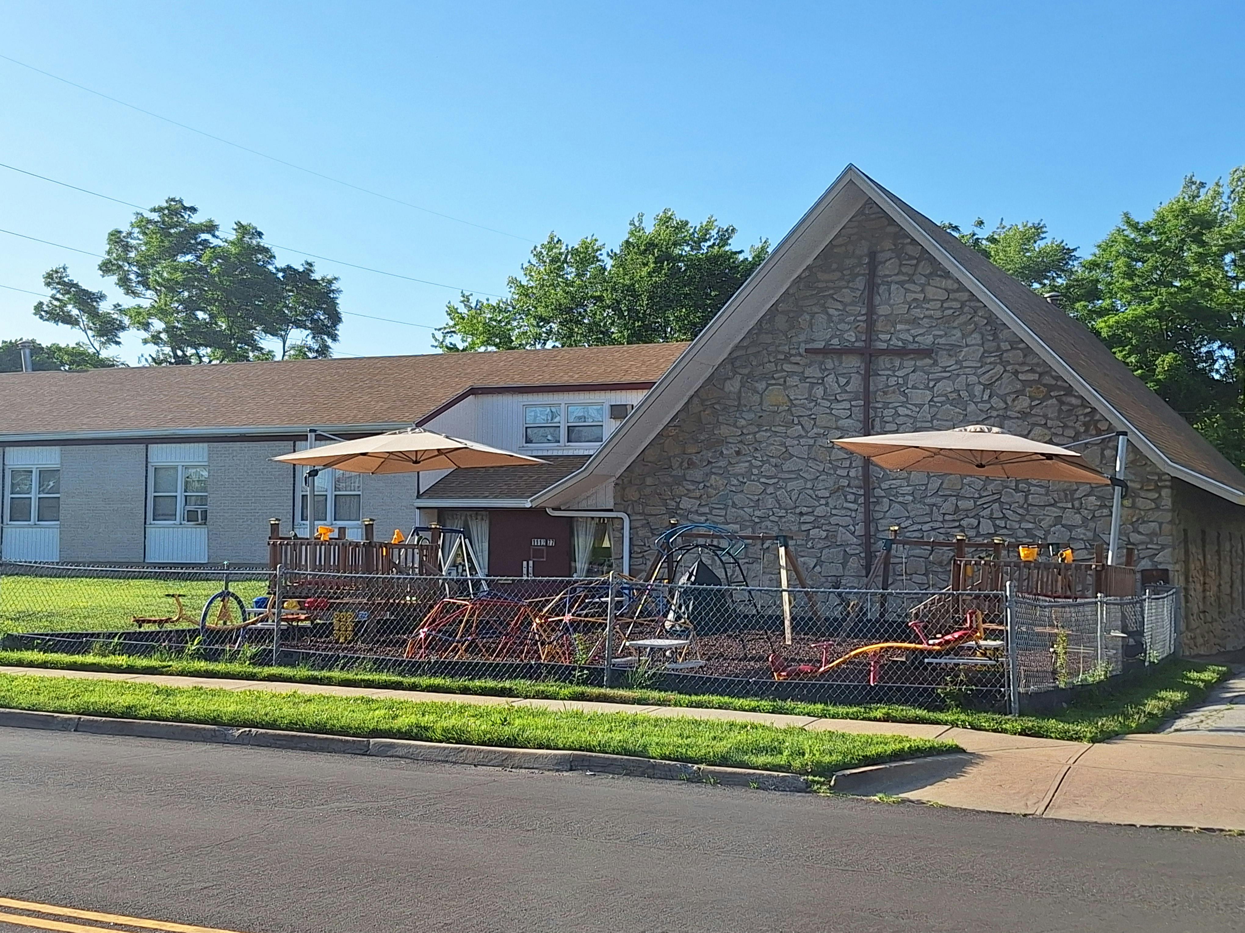 Building with a cross on the facade and a fenced-in playground area