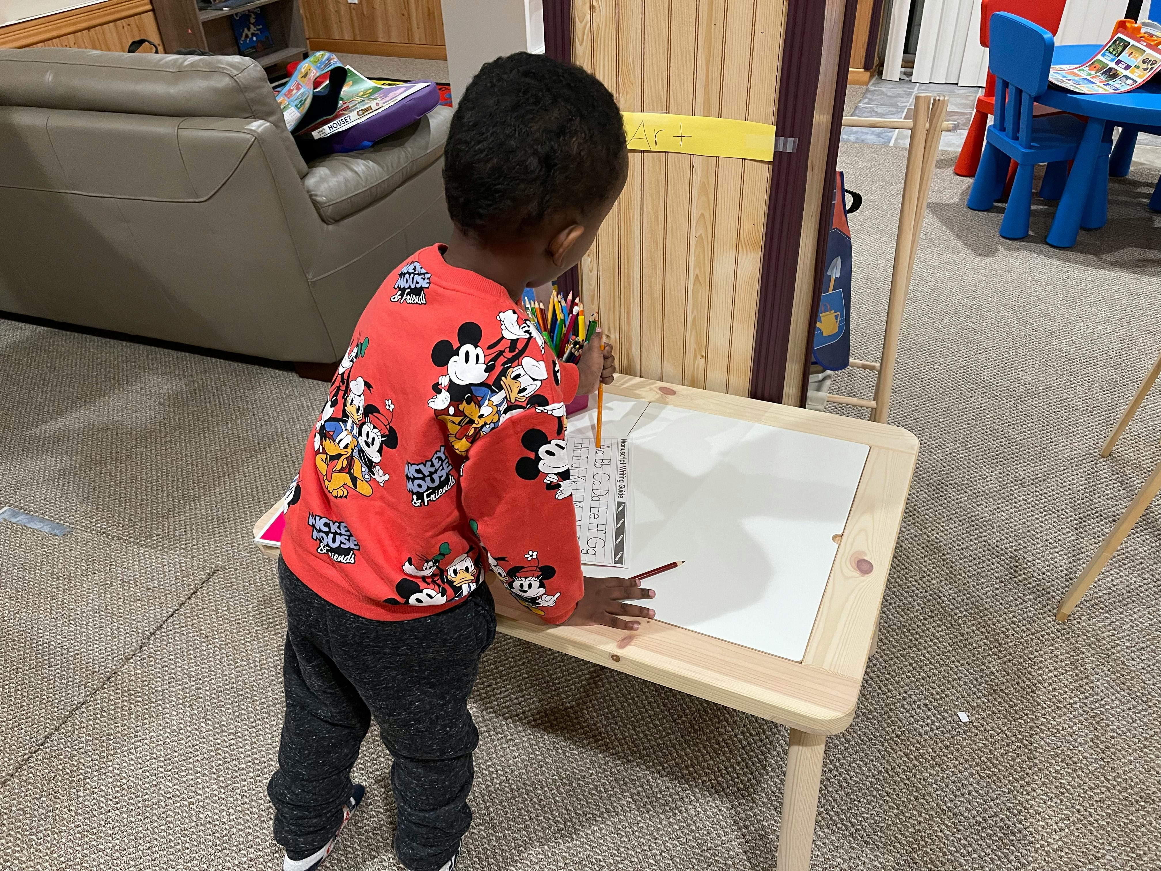 Child drawing on paper at a small table