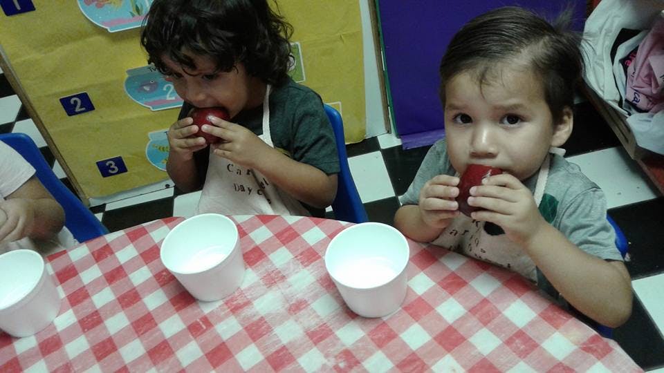 Two children eating at a table with a checkered tablecloth