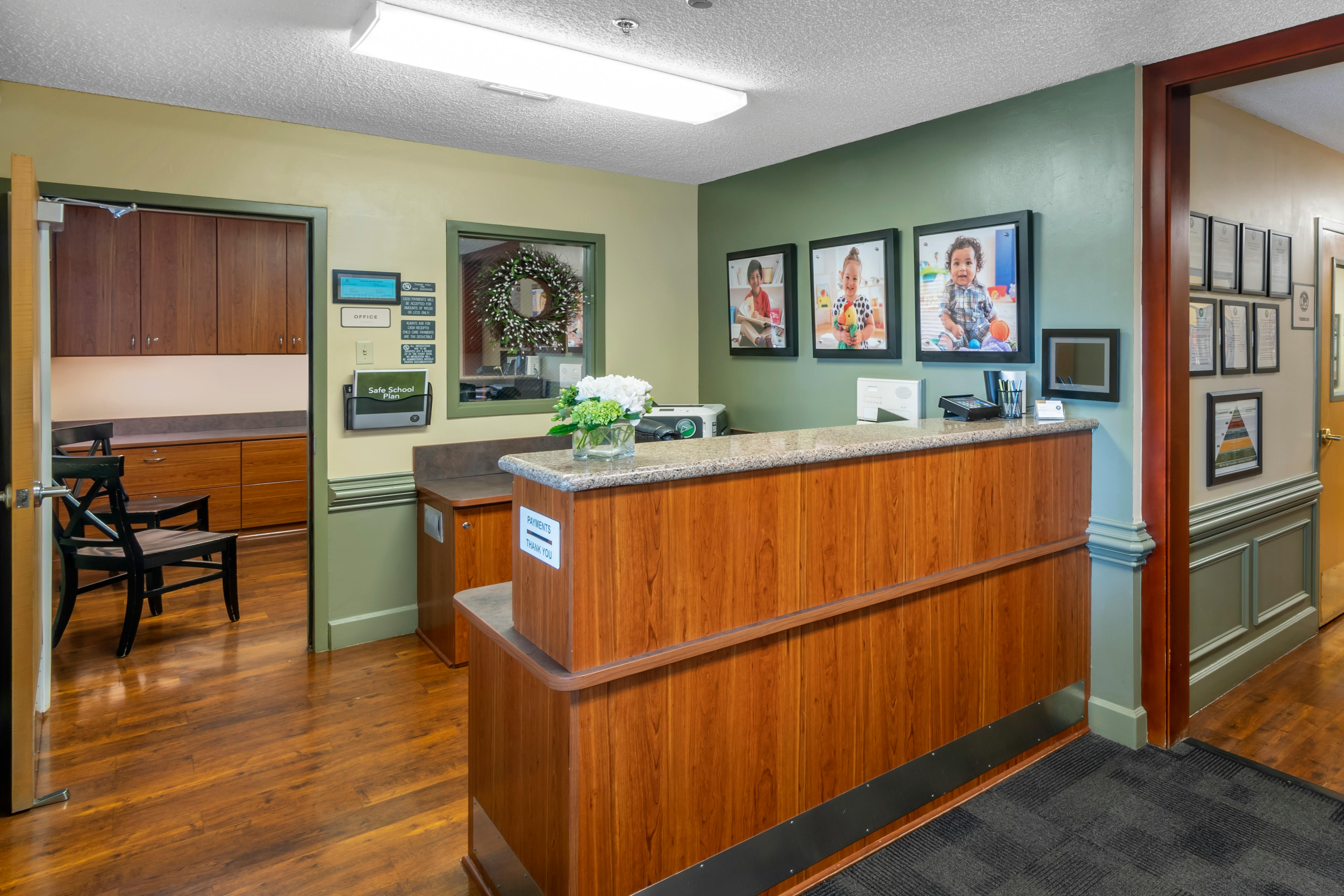 Reception desk with wood paneling and three framed photos of children on the wall