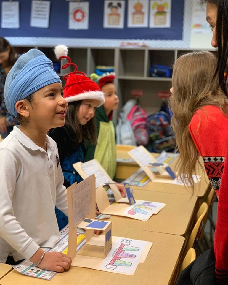 Children in a classroom looking at projects on desks