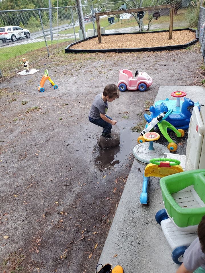 Child standing in a muddy puddle outdoors