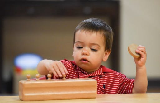 Child playing with a wooden toy on a table
