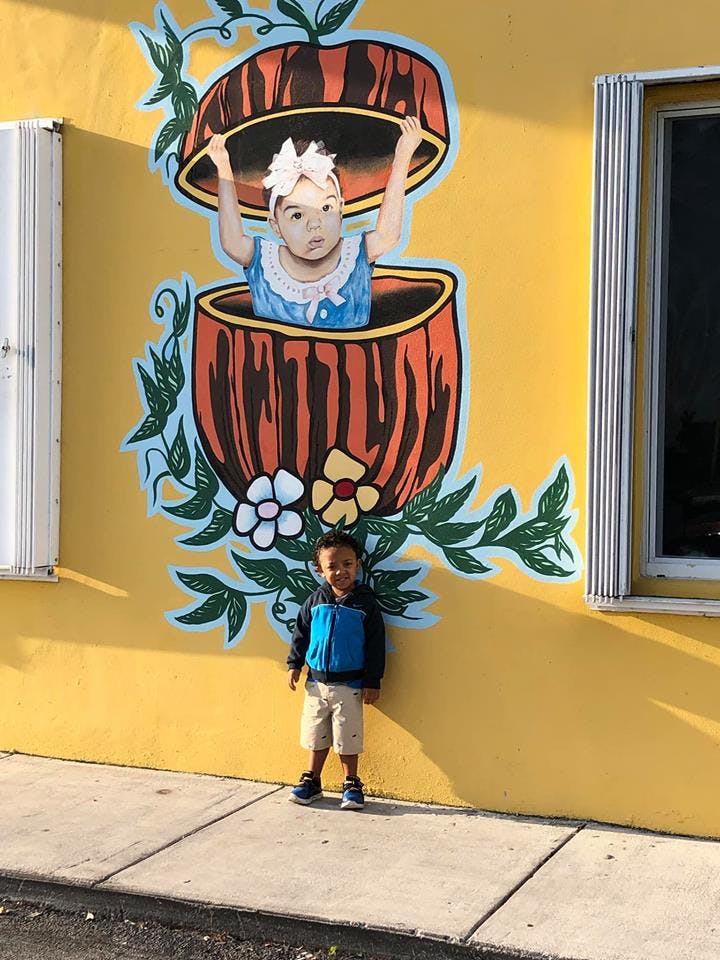 Child standing in front of a mural of a child in a pumpkin