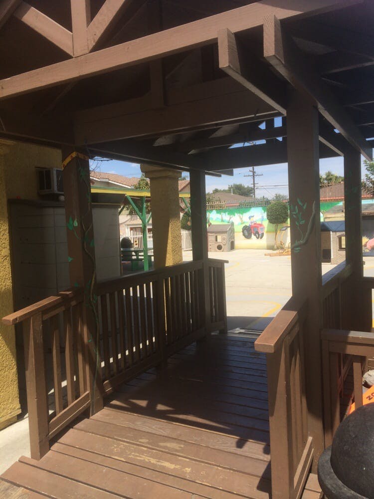 Wooden walkway with railings leading to an open area with a painted wall