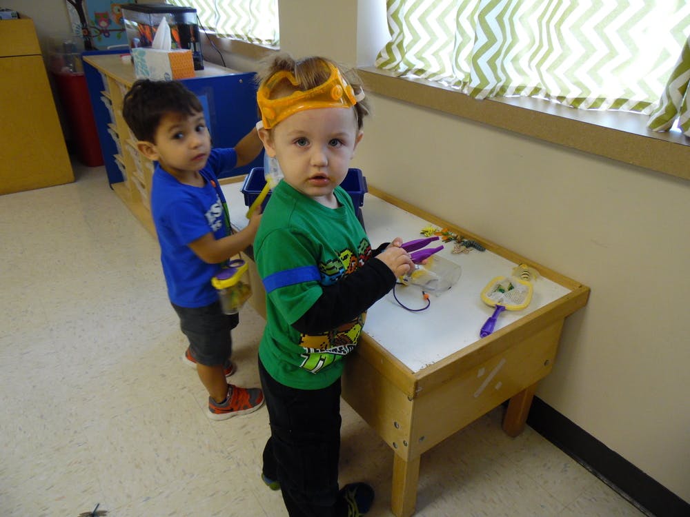 Two children playing at a sand table in a classroom