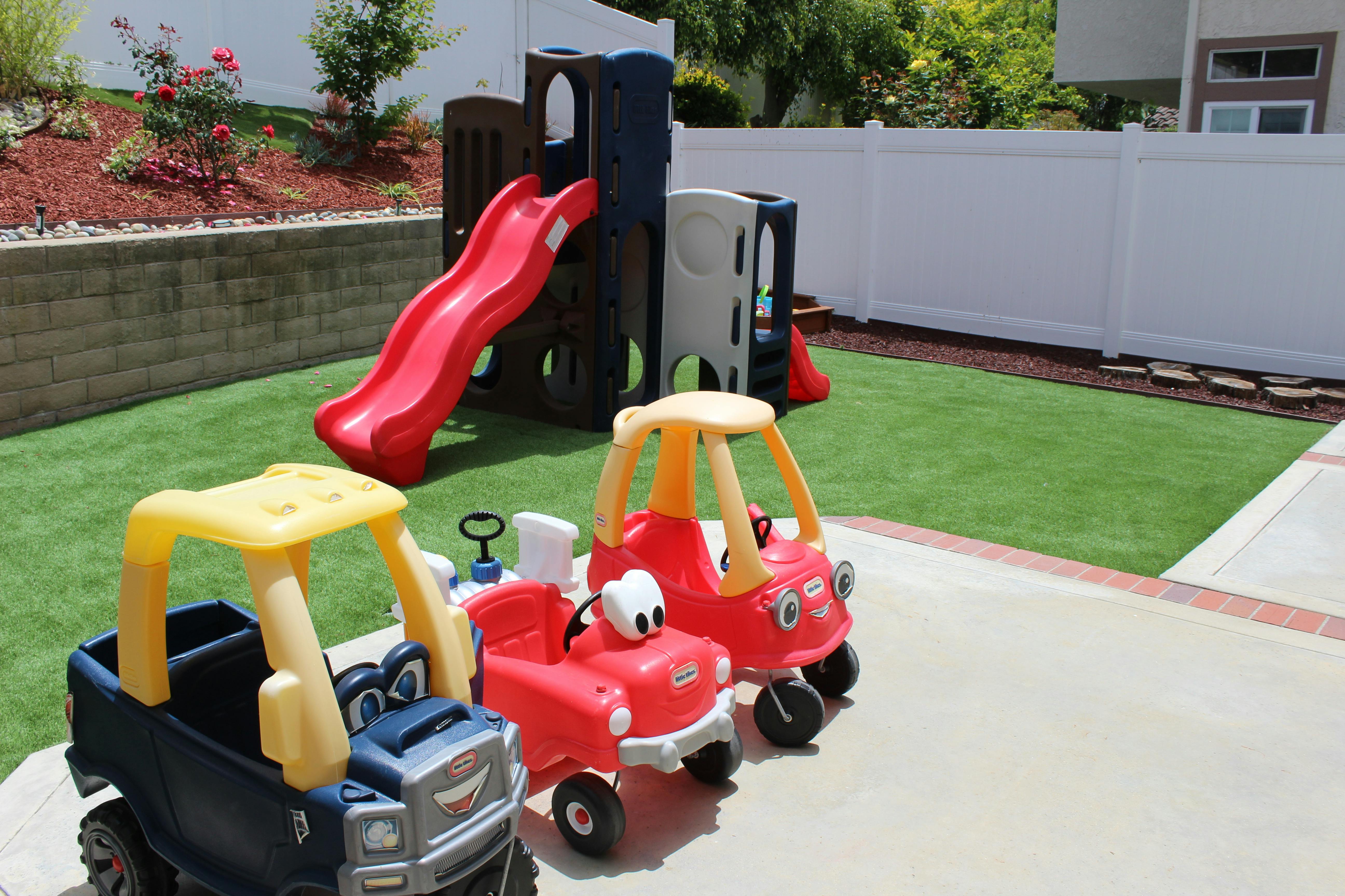 Toy cars and a playground slide on artificial grass